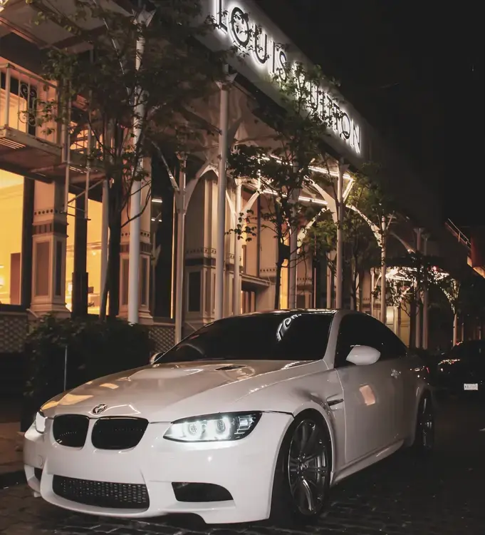 Angled view of the white BMW M3 in front of Louis Vouitton